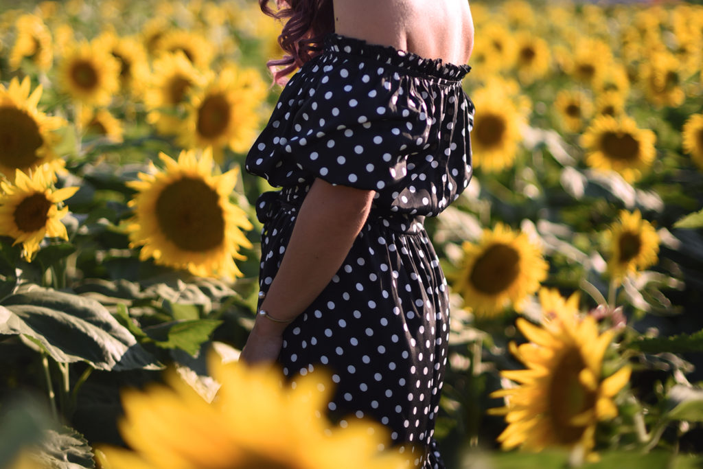 Un vestito nero lungo a pois in un campo di girasoli